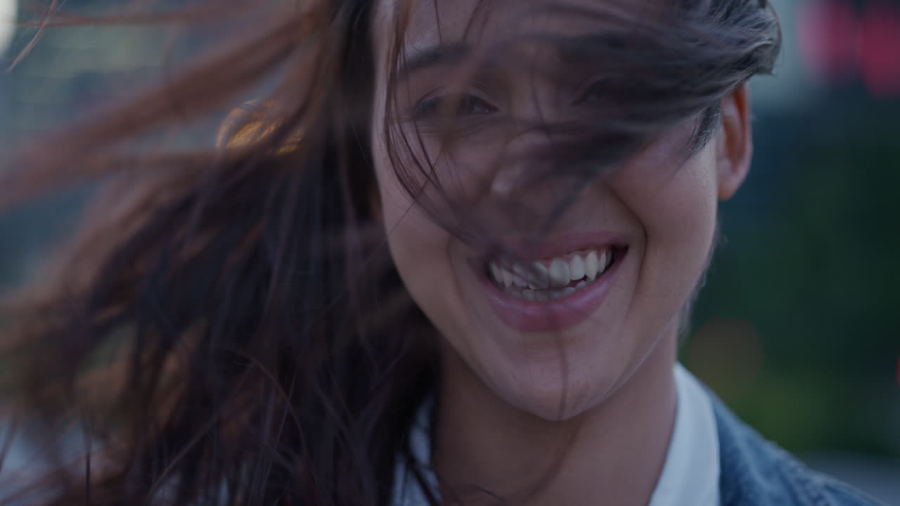 retrato de cerca hermosa joven mujer hispana riendo feliz mujer independiente disfrutando del estilo de vida en la ciudad el viento soplando el cabello cámara lenta