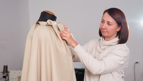 designer pins material on dress dummy, shaping garment with precision, ensuring neat fit, focusing on details, skillful draping, showcasing creative approach, demonstrating professional finishing