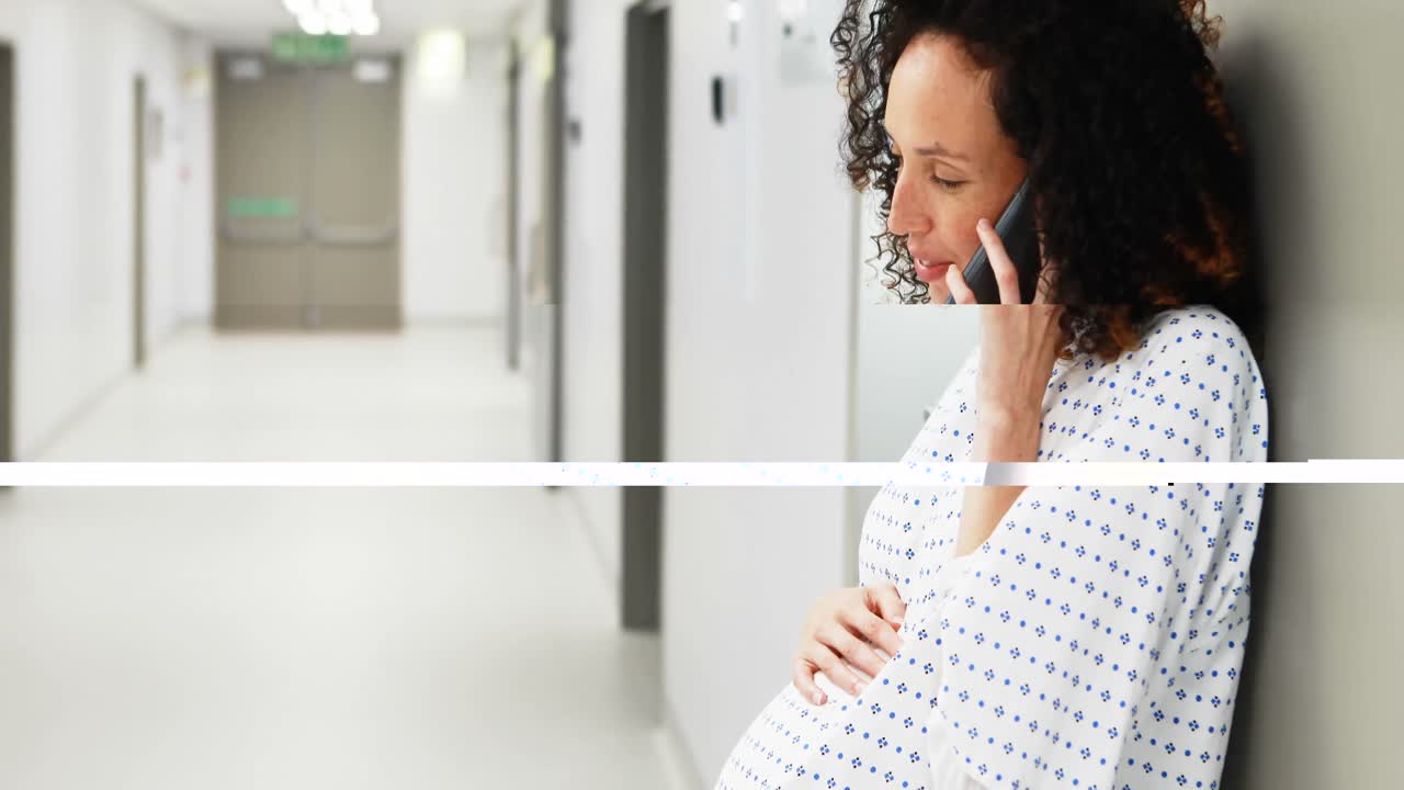 Pregnant woman talking on mobile phone in corridor