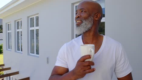 front view of mature caucasian man having coffee in balcony at home 4k