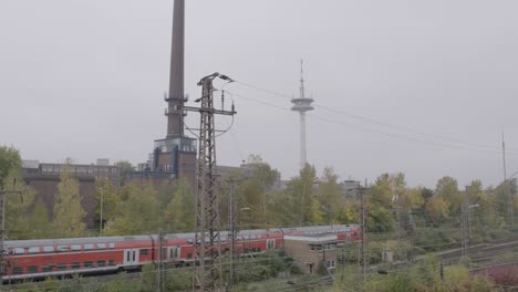 tren rojo pasando por un área industrial en un día nublado