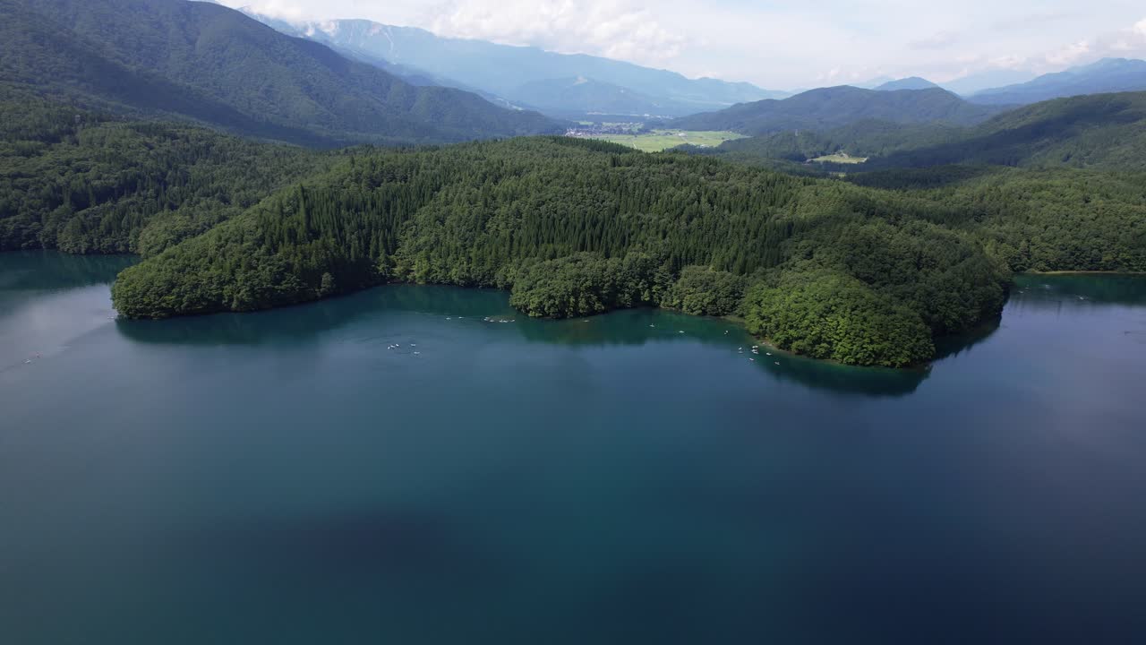 Flying Over Lake Aoki Towards The Mountain Forest With Green Trees In Omachi, Japan. - aerial shot