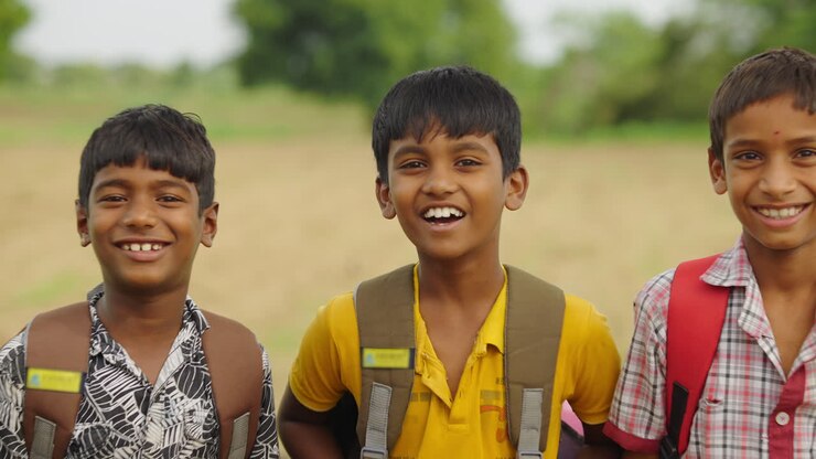 Three school children with backpacks in a rural setting