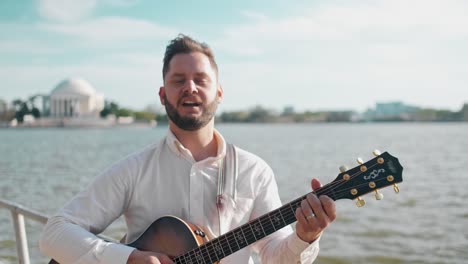 Artista-Adulto-Cantando-Y-Tocando-Su-Guitarra-En-El-Memorial-De-Thomas-Jefferson-En-Washington-Dc-Durante-El-Festival-De-Los-Cerezos-En-Flor-En-Una-Tarde-Luminosa-Y-Soleada