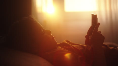 child using phone in bed at sunrise/sunset