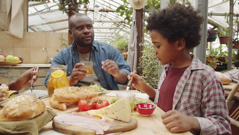 african american family eating dinner in greenhouse