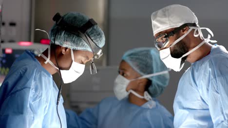 diverse surgeons wearing surgical gowns operating on patient in operating theatre, slow motion