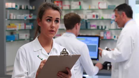 Junior-pharmacist-writing-on-clipboard