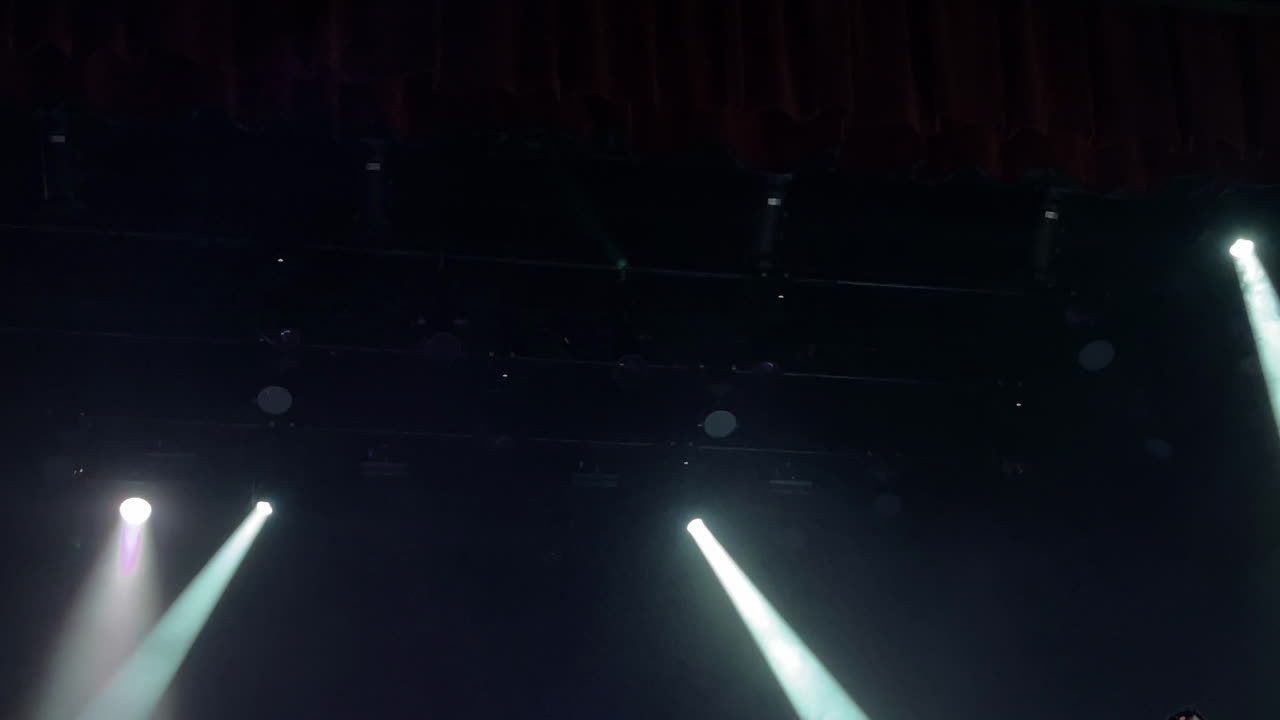 Stage lighting beams illuminating a dark theater space creating a dramatic atmosphere