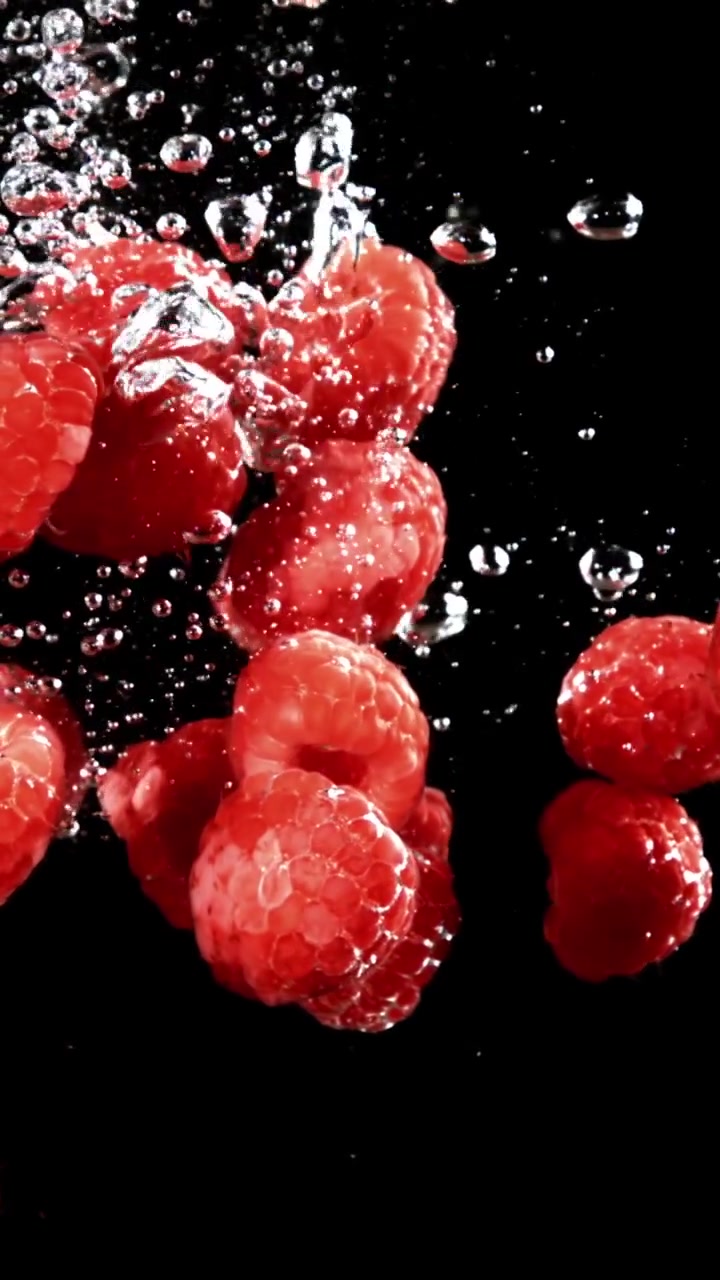 Red Raspberries Dropping into Water in Slow Motion