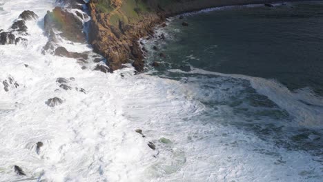aerial view of powerful ocean waves crashing against rocky cliffs at byron bay, australia, under bright daylight