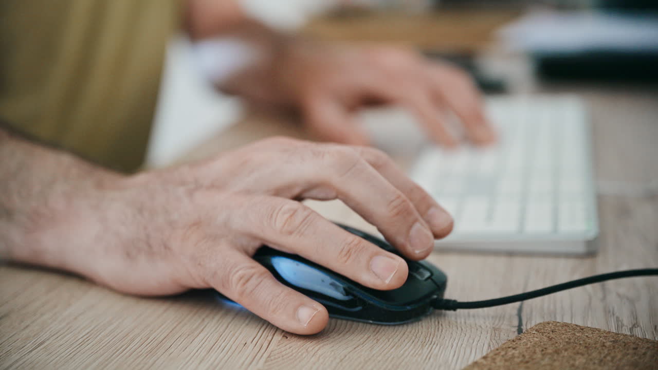 Close-up of hands using computer mouse and keyboard at desk for office work and productivity, 4K