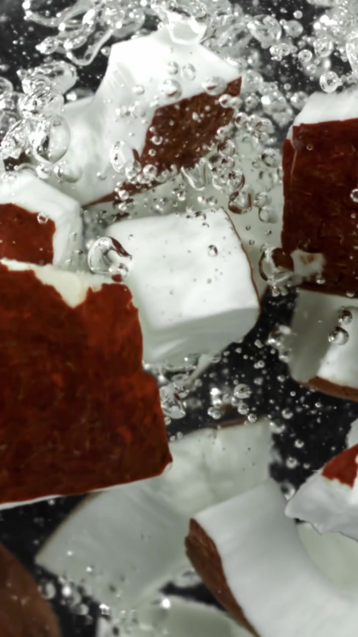 Rallentatore di pezzi di cocco che cadono nell'acqua con bollicine
