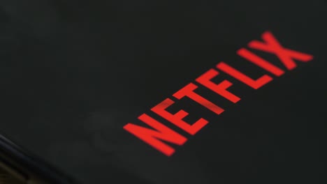 smartphone with various app icons, finger touching netflix icon