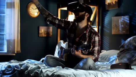 침대에 vr 안경으로 기타를 연주하는 남자