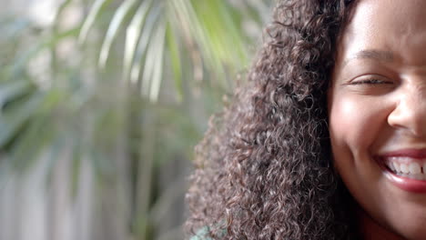 Half-portrait-of-happy-african-american-woman-smiling-by-sunny-plants,-copy-space,-slow-motion