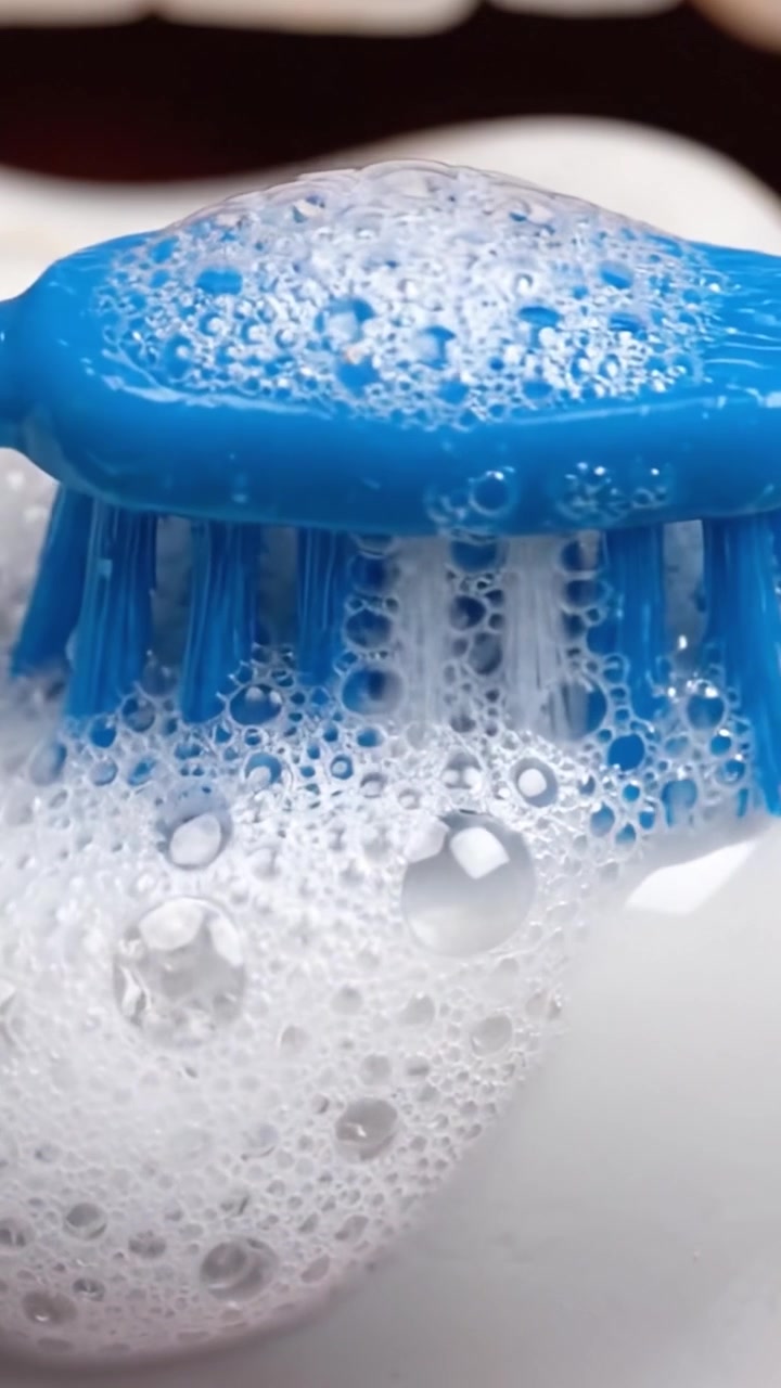 Primo piano di uno spazzolino da denti che raccoglie schiuma dal dentifricio, evidenziando l'igiene orale e la pulizia nella routine quotidiana di cura dentale.