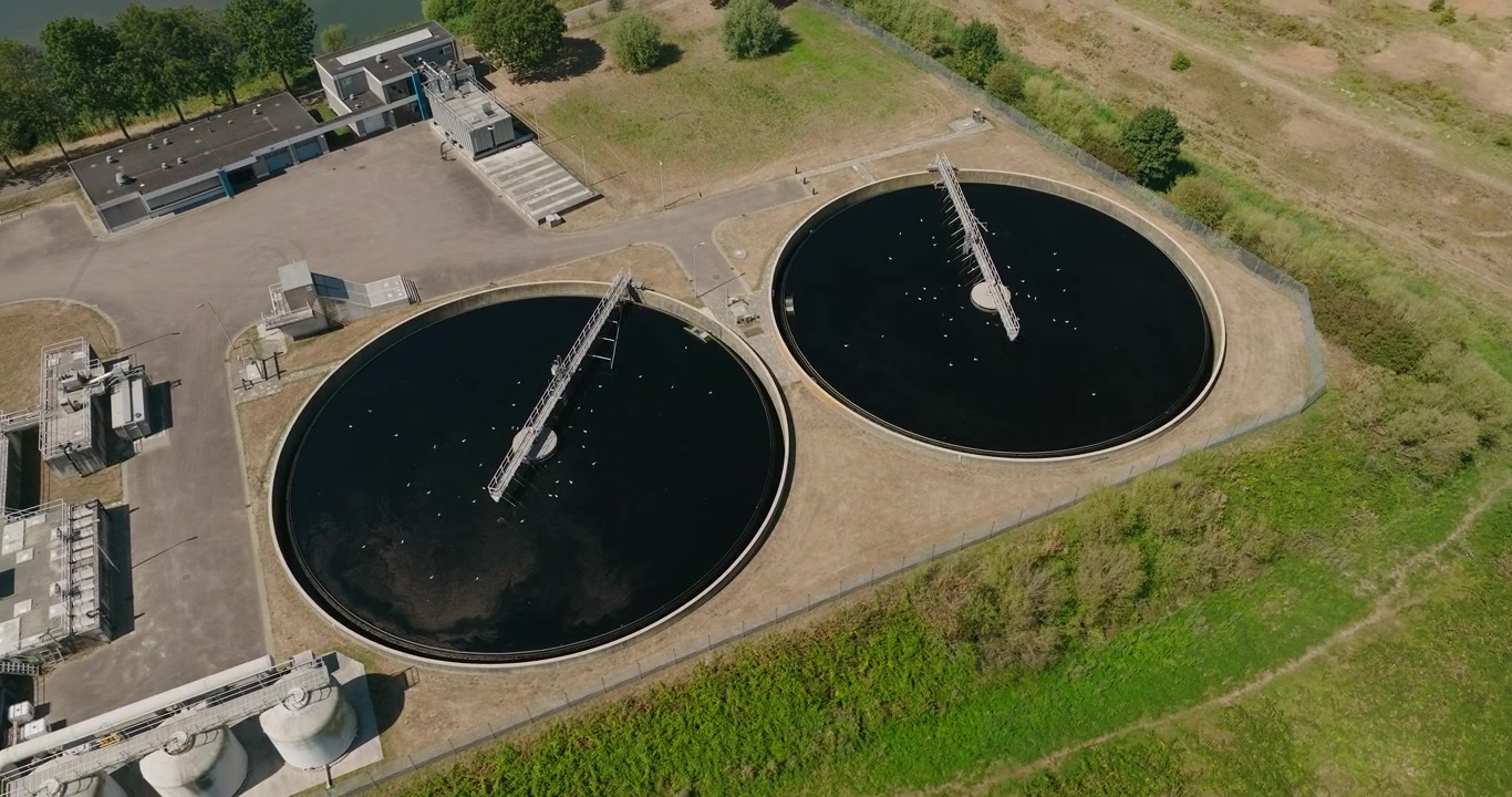 Drone orbits around large sedimentation basins at a water treatment plant, showing water purification infrastructure and the process of separating solids from wastewater.