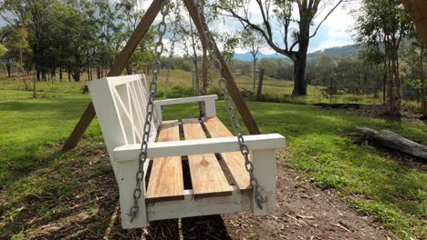 Empty-wooden-chair-swings-in-countryside-field-with