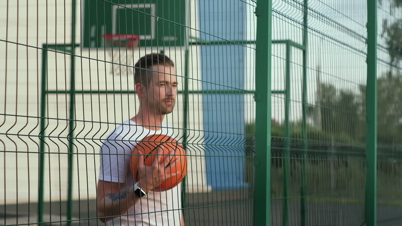 hombre con baloncesto por una valla de la cancha