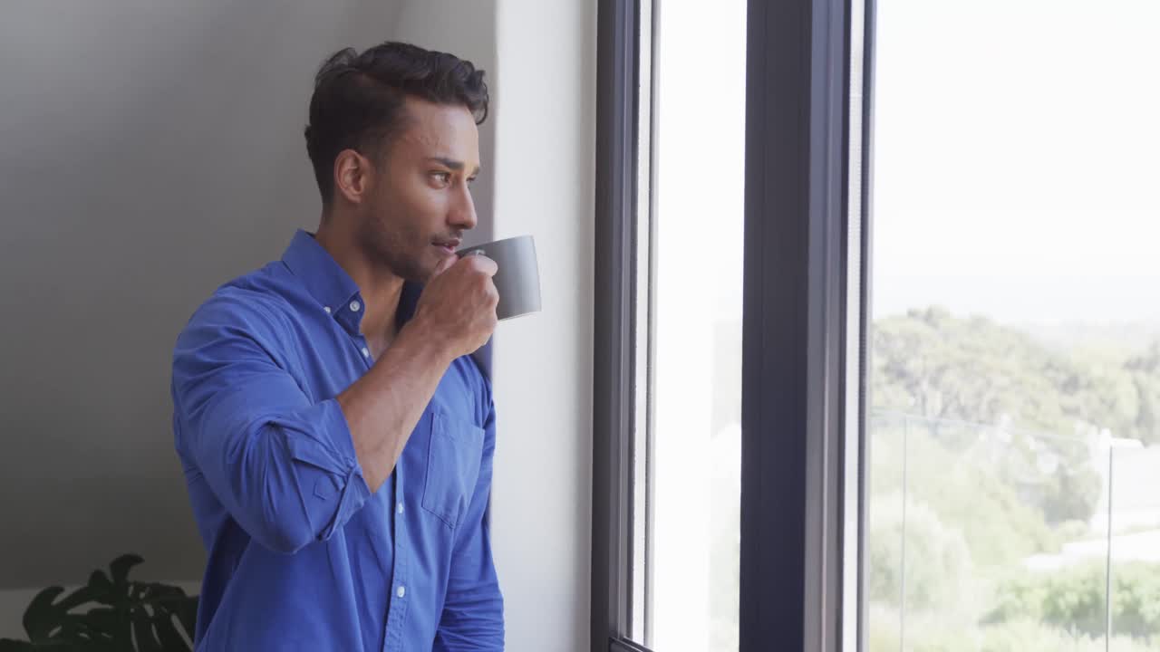 커피를 마시고 슬로우 모션으로 창문 밖을 바라보는 행복한 두 인종 남성