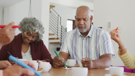 happy senior diverse people drinking tea and playing bingo at retirement home