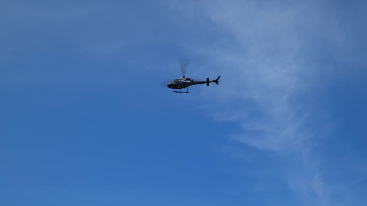 지상에서 본 검은 헬리콥터 지나가는 돌리 추적 샷