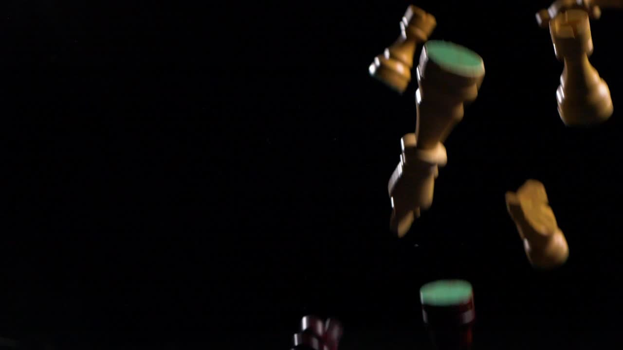 cámara lenta de piezas de ajedrez lanzadas al aire sobre un fondo negro