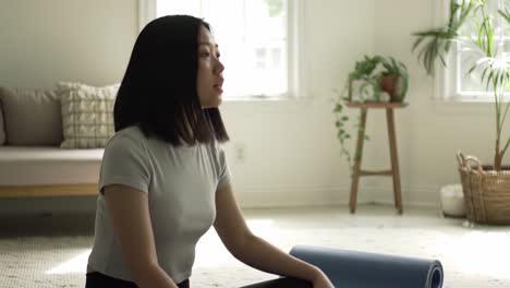 a serene moment of reflection: a young woman sitting calmly in a minimalist room, engaging with her thoughts while seated beside a yoga mat