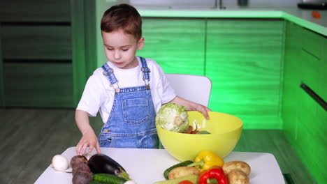 child preps veggies for cooking. a child in overalls gathers fresh vegetables in a bowl while cooking in a modern kitchen with green lighting