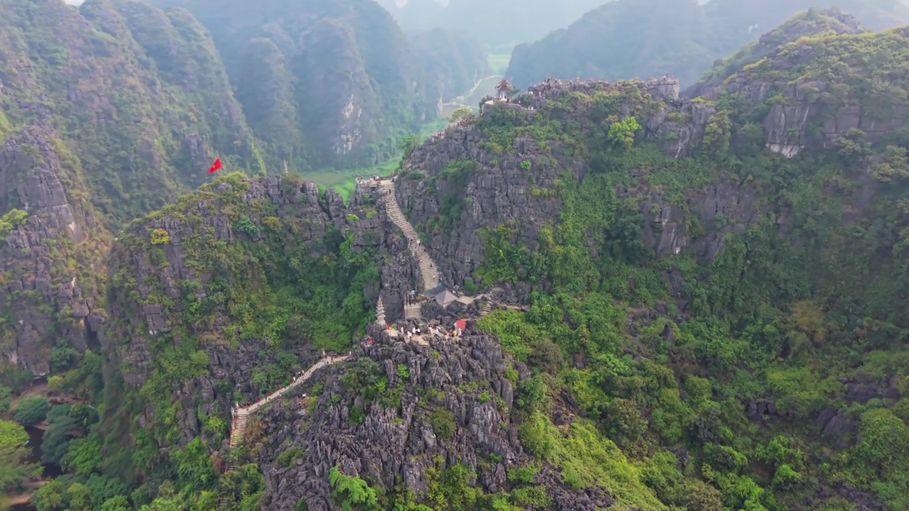 Cảnh quay drone ghi lại hình ảnh du khách leo lên những bậc thang đá tuyệt đẹp dẫn lên đỉnh Hang Múa ở miền Bắc Việt Nam