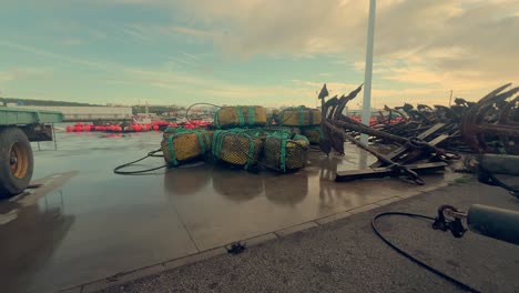 Los-Equipos-De-Pesca-Se-Colocan-Sobre-El-Asfalto-Húmedo-En-Una-Ciudad-Costera-De-España,-Con-Anclas-Y-Redes-Metálicas,-Que-Encarnan-La-Esencia-Del-Sustento-Marítimo-Y-El-Patrimonio-Costero.