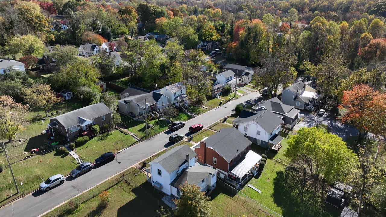 Aerial view of American suburban neighborhood in autumn, with colorful fall trees, quiet streets and classic single-family homes under bright daylight. Top down shot. Virginia, USA
