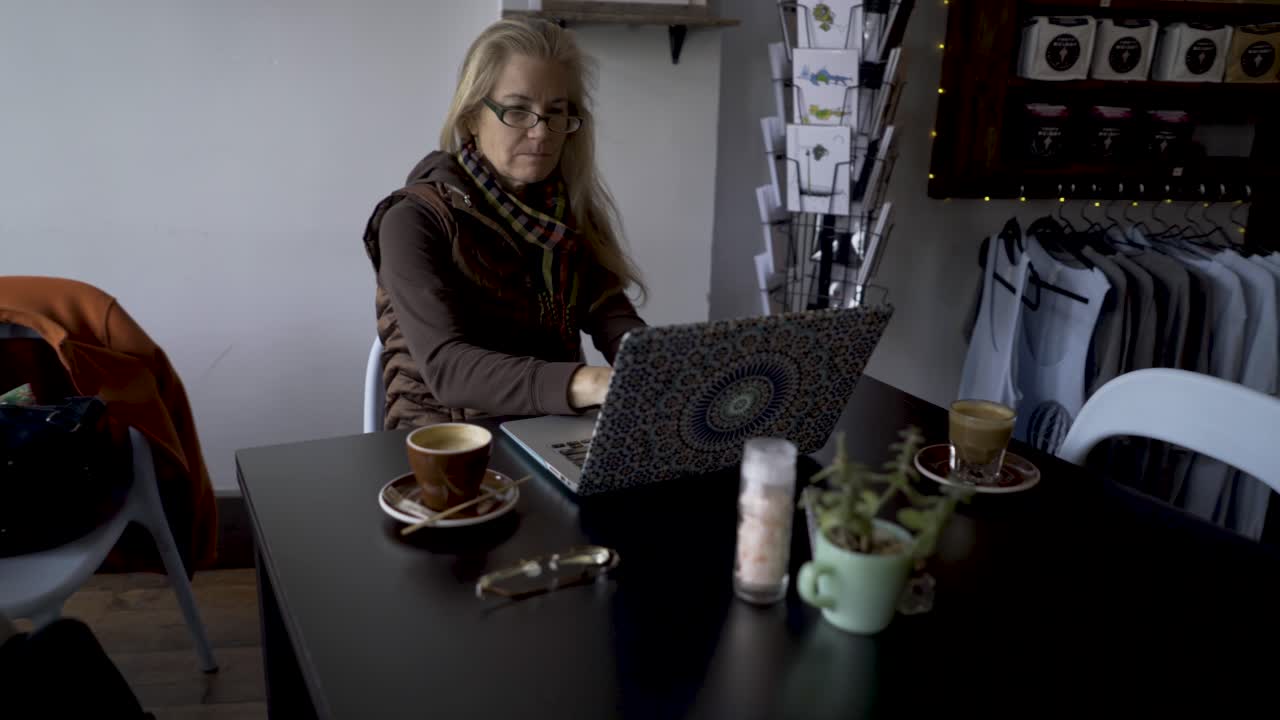 Donna che lavora al computer portatile in un caffè