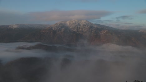 static shot of mist passing infront of a snow-covered ben venue from ben a'an