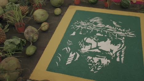 slow pan across a artwork of jesus with a crown of thorns made out of sand in guatemala