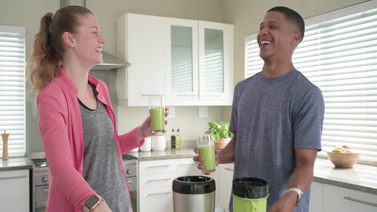 Mangfoldigt par laver grønne smoothies derhjemme for at smage dem til, mand fjerner låget fra blenderkoppen
