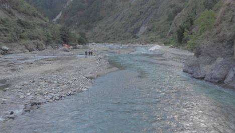 three men hiking trekking backpacking down natural mountain water river rapids flowing through valley in remote region fast wide approaching aerial over white water rapids rocks boulders philippines