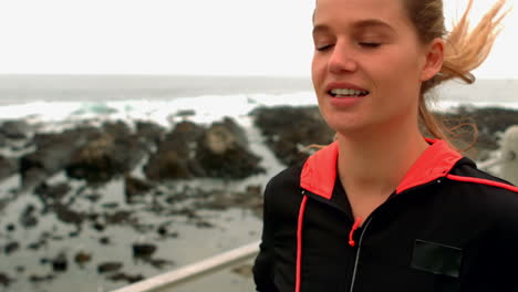 Smiling-sporty-woman-jogging-at-promenade