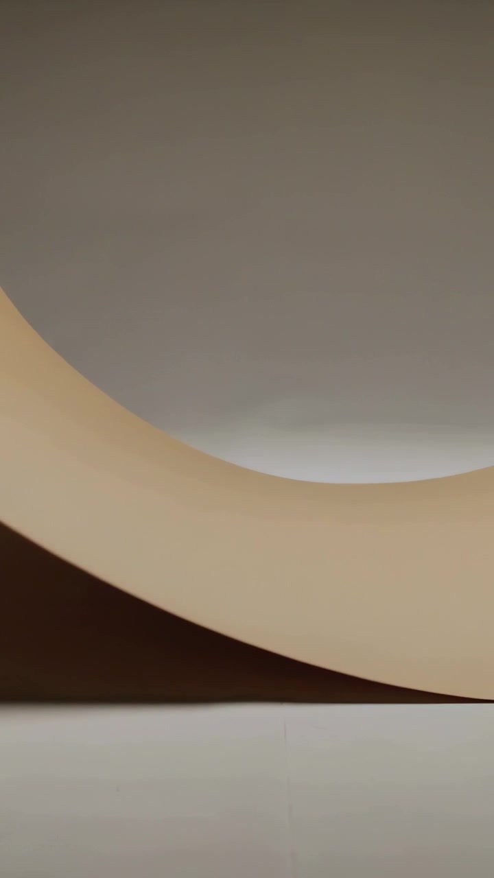 Vertical video: Releasing flexible beige sheet sweeping across table, forming curved band at center