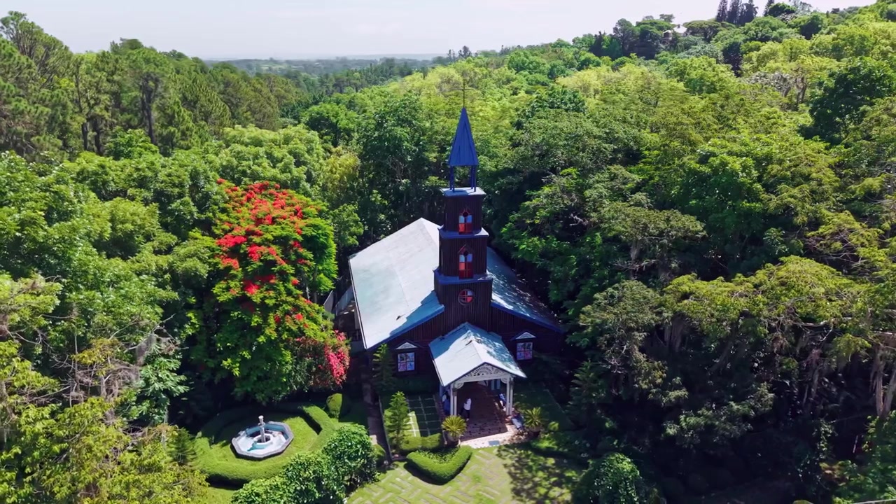 Vista de dron de la rústica iglesia de madera Capilla La Milagrosa escondida entre densos árboles verdes y vegetación tropical en República Dominicana. Órbita aérea.