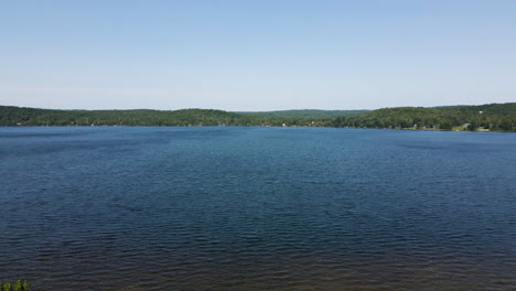 Slow-motion-push-in-over-trees-to-empty-clear-blue-lake-on-sunny-day