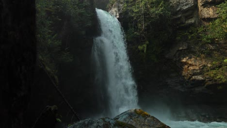 reveal of an elegant waterfall from behind a rock in british columbia, canada
