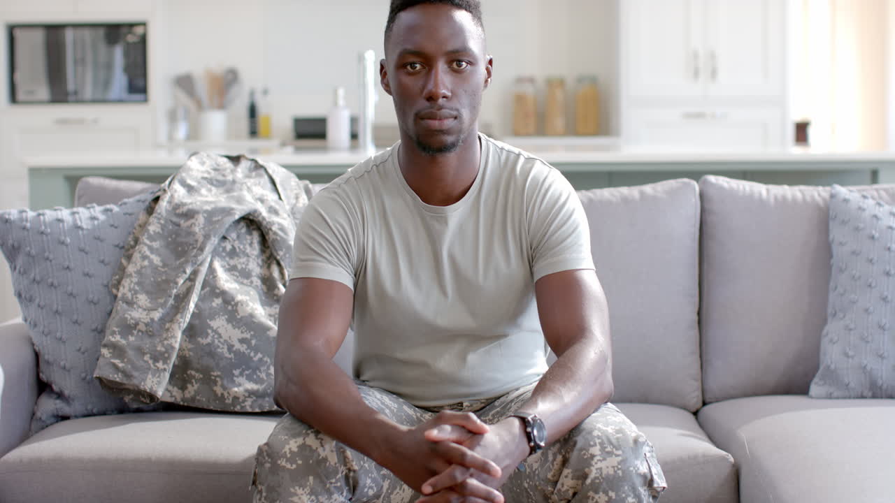 Jovem soldado afro-americano senta-se confiantemente em casa, com espaço para texto