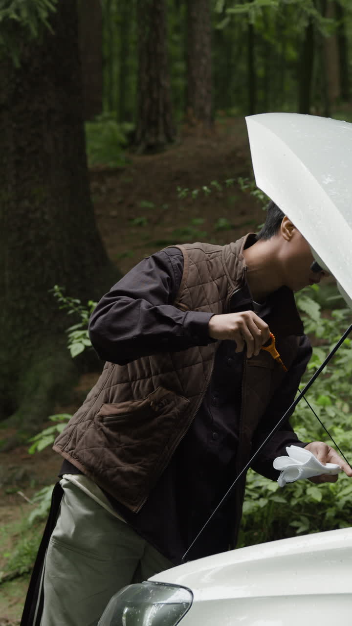 Man checking car oil level in forest