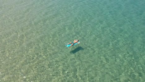 Guy-floats-on-a-inflatable-mattress-in-the-Aegean-sea-in-town-of-Skala-Sotiros-Greece