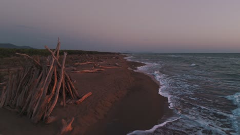 wooden tipi at a natural beach during sunset