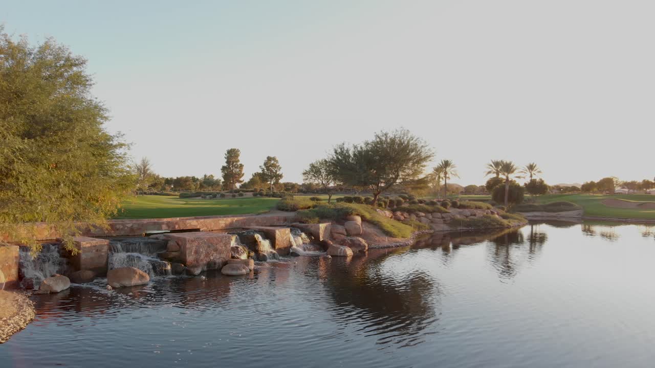 Drone footage from a golf course near a residential neighborhood in Arizona. Low aerial shot of a water hazard