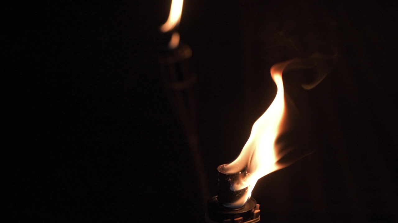 dos antorchas de boda ardiendo en la oscuridad, cerca de la toma estática con fondo negro