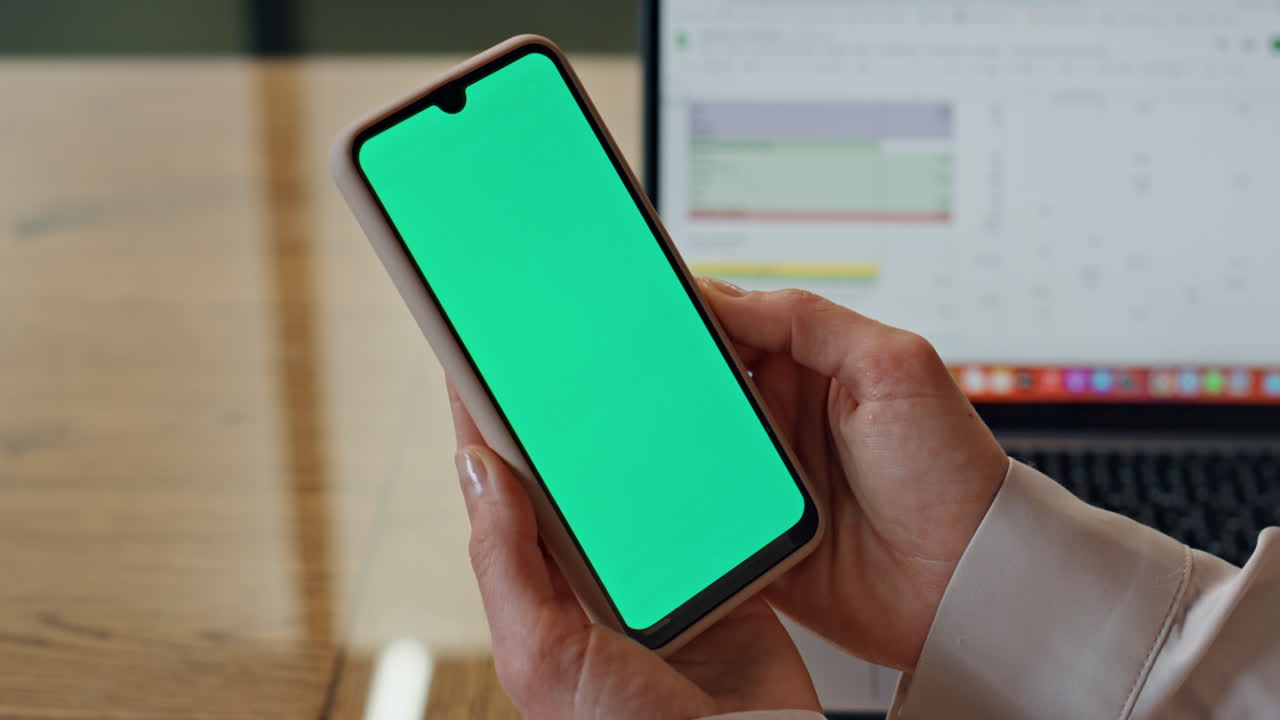 Dita di donna che tengono un mockup di cellulare, primo piano. Donna che legge sul cellulare con schermo verde